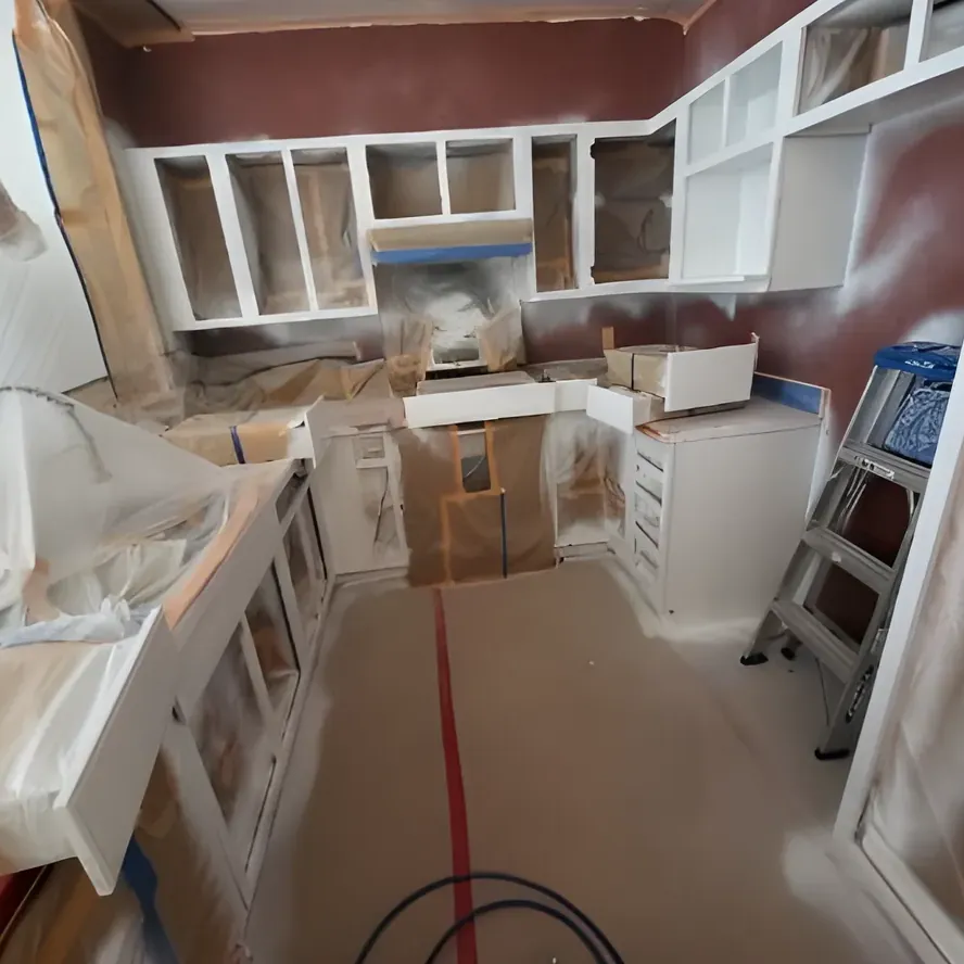 A kitchen interior being painted inside plastic sheeting, the floor covered in paper