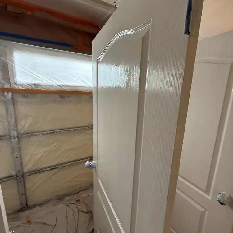 A room sealed floor to ceiling in plastic sheeting, with an interior door freshly painted